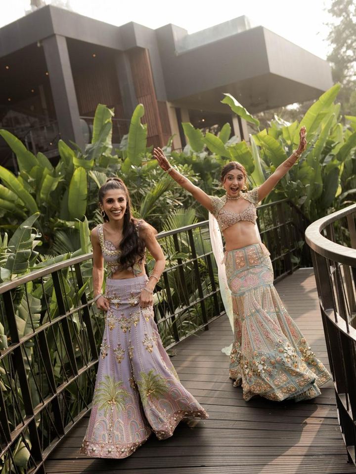Two women dancing in pastel lehengas