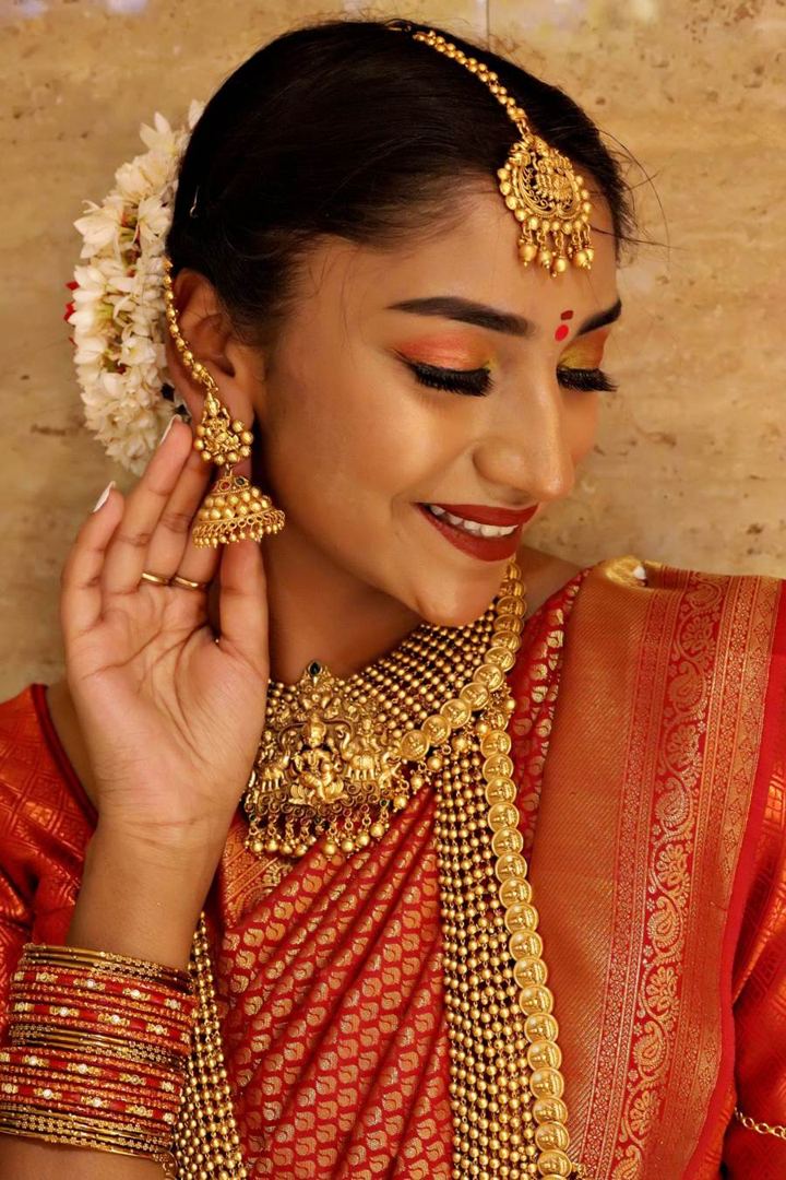 Bride in a red and gold silk saree with temple jewellery